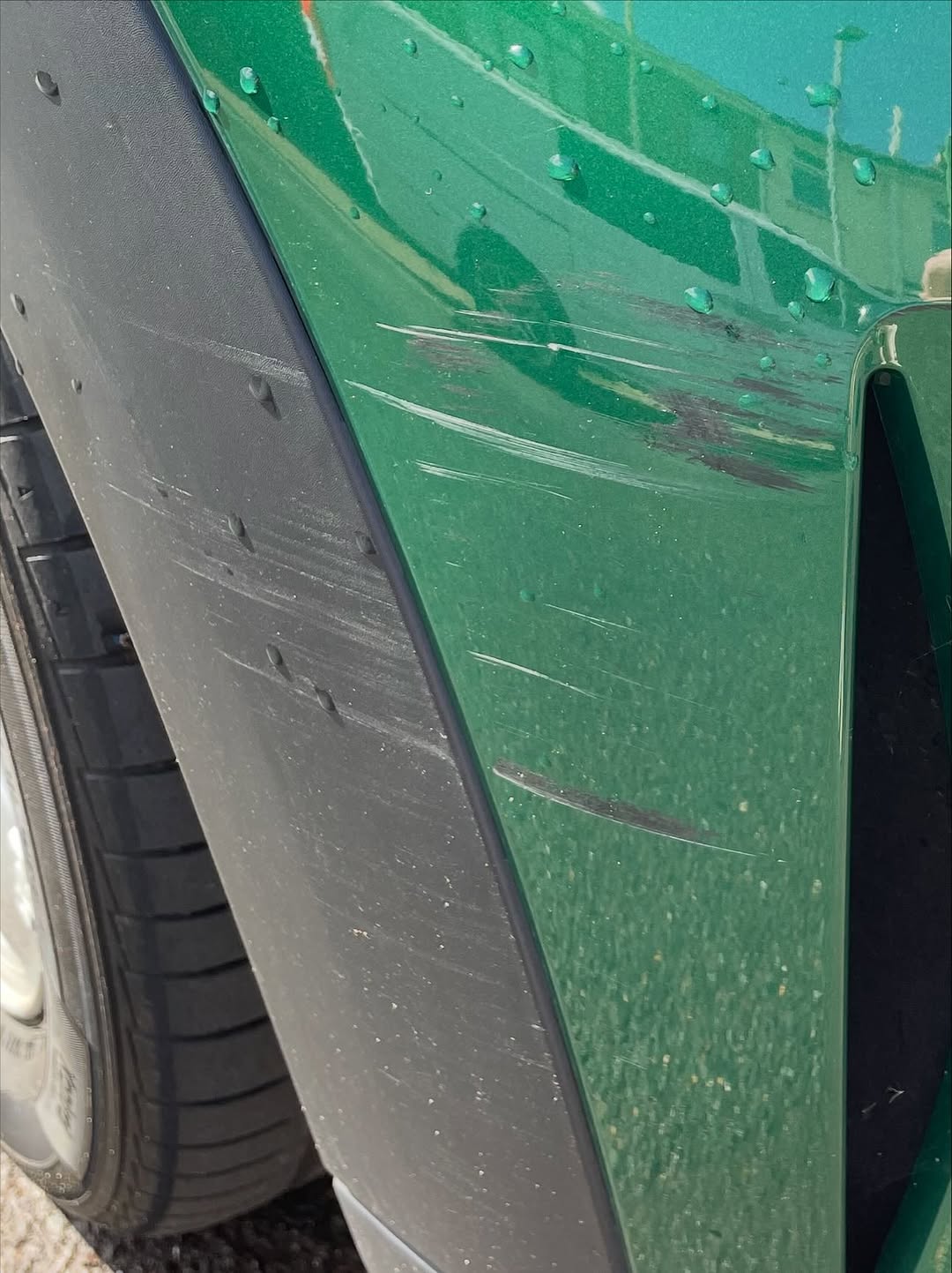 Deep scratches on a green Mini front wing before repair